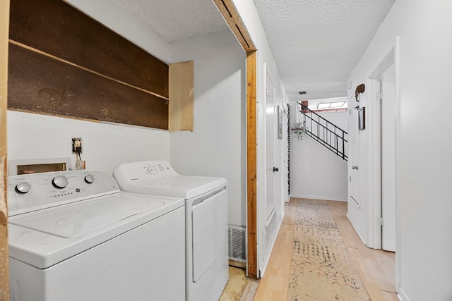 706 Cambridge Dr, Round Rock, TX 78664 - washroom featuring light wood-style floors, washing machine and clothes dryer, and a textured ceiling