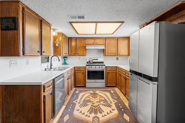 706 Cambridge Dr, Round Rock, TX 78664 - kitchen featuring stainless steel appliances, under cabinet range hood, a textured ceiling, light countertops, and brown cabinets