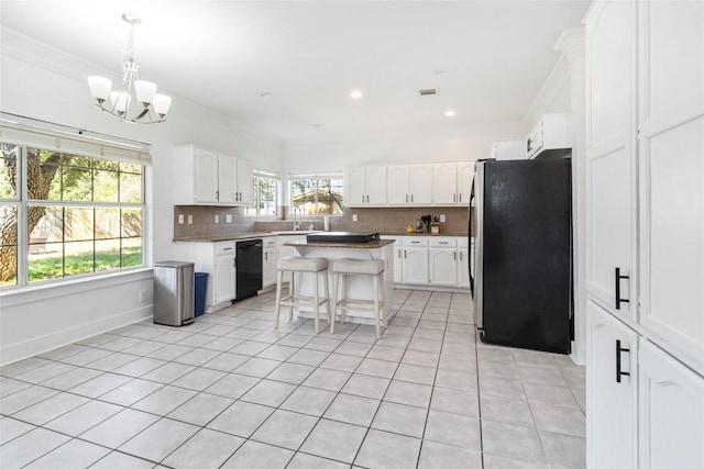 6100 Open Range Trl, Austin, TX 78749 - kitchen with freestanding refrigerator, black dishwasher, a chandelier, tasteful backsplash, and light tile patterned flooring