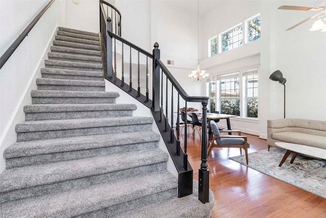 6100 Open Range Trl, Austin, TX 78749 - stairs featuring wood finished floors, a towering ceiling, ceiling fan, and a chandelier