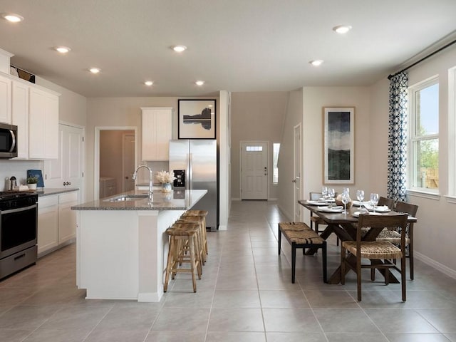 716 Sun Grove Trl, Georgetown, TX 78628 - kitchen with appliances with stainless steel finishes, stone counters, a kitchen island with sink, recessed lighting, and a breakfast bar area