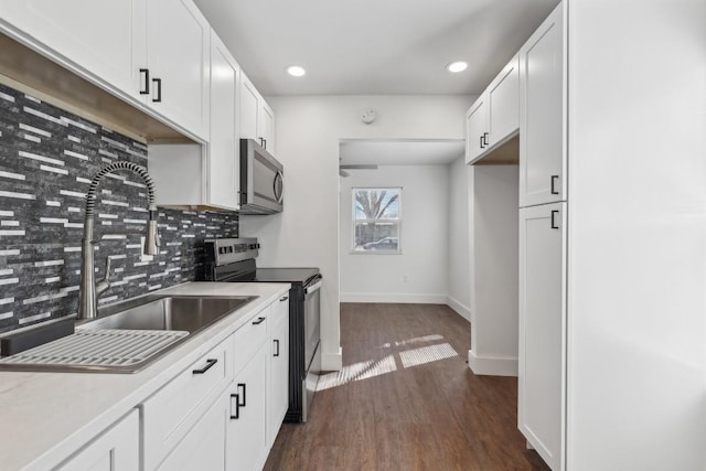 304 Harris St, Smithville, TX 78957 - kitchen featuring stainless steel appliances, backsplash, dark wood-type flooring, white cabinetry, and recessed lighting