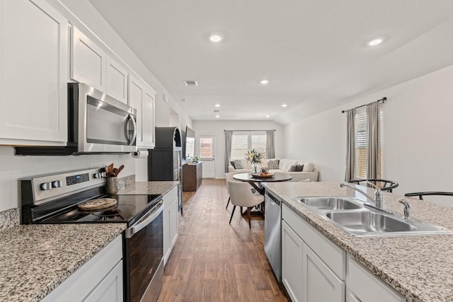 11817 Rush Ln, Elgin, TX 78621 - kitchen with stainless steel appliances, wood finished floors, white cabinets, open floor plan, and recessed lighting