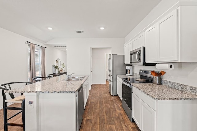 11817 Rush Ln, Elgin, TX 78621 - kitchen featuring stainless steel appliances, white cabinets, dark wood-style floors, a center island with sink, and a breakfast bar