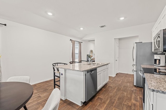 11817 Rush Ln, Elgin, TX 78621 - kitchen featuring stainless steel appliances, an island with sink, white cabinetry, dark wood-style floors, and lofted ceiling