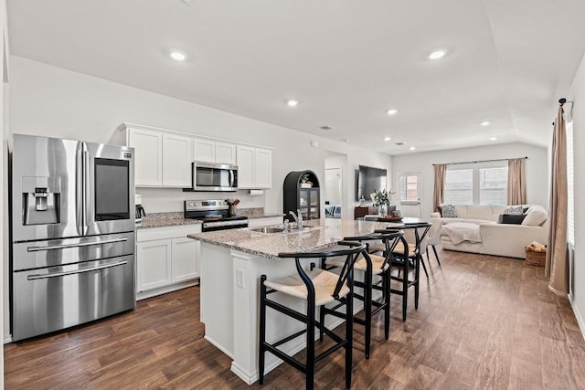 11817 Rush Ln, Elgin, TX 78621 - kitchen featuring appliances with stainless steel finishes, dark wood finished floors, recessed lighting, white cabinets, and a kitchen island with sink