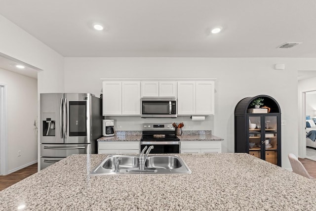 11817 Rush Ln, Elgin, TX 78621 - kitchen featuring stainless steel appliances, white cabinets, dark wood-style flooring, recessed lighting, and light stone countertops