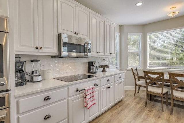 704 Deckhouse Dr, Lago Vista, TX 78645 - kitchen with stainless steel microwave, black electric cooktop, tasteful backsplash, white cabinets, and light wood-type flooring