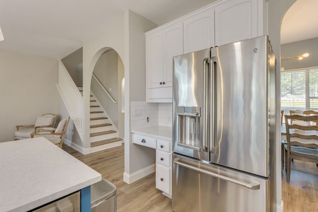 704 Deckhouse Dr, Lago Vista, TX 78645 - kitchen featuring stainless steel refrigerator with ice dispenser, arched walkways, white cabinetry, light wood-style flooring, and light countertops