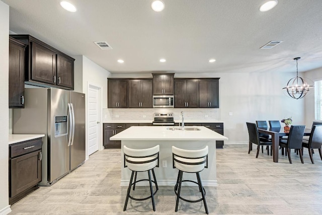 817 Choya Trl, Leander, TX 78641 - kitchen with stainless steel appliances, light countertops, dark brown cabinets, light wood finished floors, and a chandelier