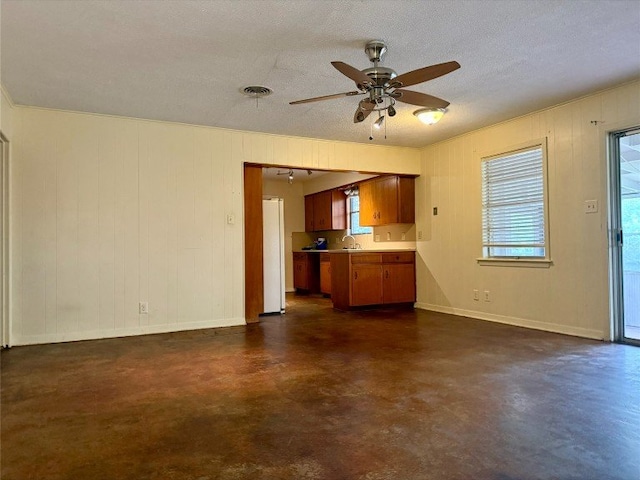11601 Oak Trl, Austin, TX 78753 - unfurnished living room featuring a ceiling fan, finished concrete floors, a textured ceiling, and wood walls