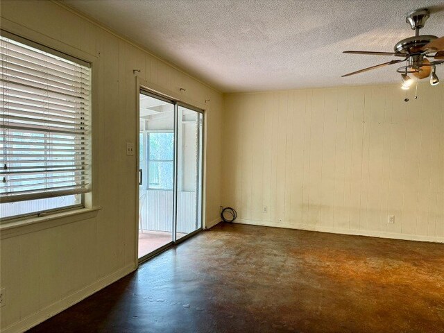 11601 Oak Trl, Austin, TX 78753 - spare room featuring concrete floors, ceiling fan, a textured ceiling, and wooden walls