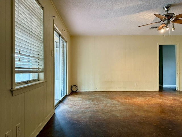11601 Oak Trl, Austin, TX 78753 - empty room with concrete flooring, a ceiling fan, a textured ceiling, and wooden walls