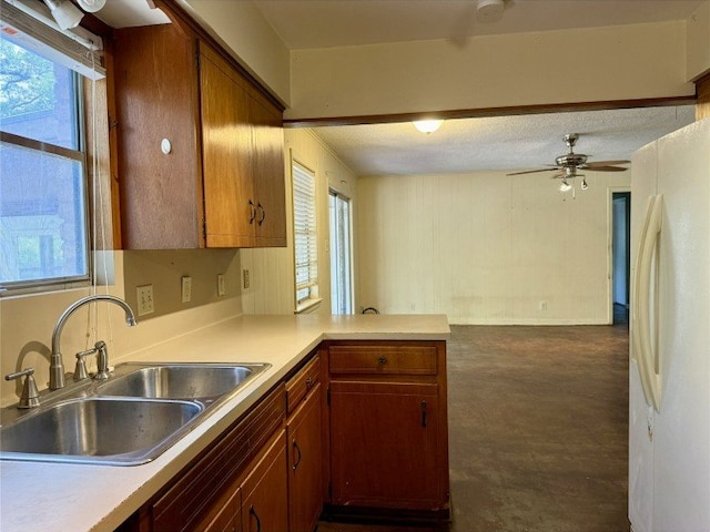 11601 Oak Trl, Austin, TX 78753 - kitchen featuring freestanding refrigerator, light countertops, a peninsula, ceiling fan, and brown cabinetry