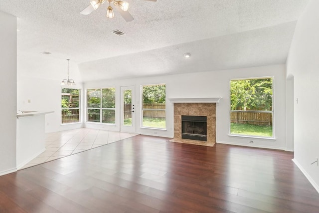 800 Mountain Ridge Dr, Leander, TX 78641 - unfurnished living room featuring a textured ceiling, a ceiling fan, a tile fireplace, wood finished floors, and a chandelier