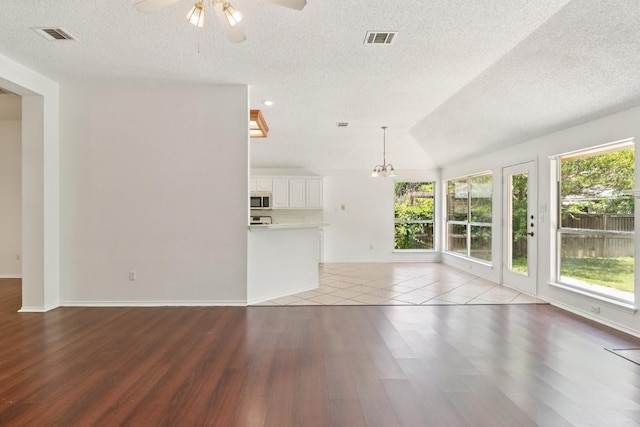 800 Mountain Ridge Dr, Leander, TX 78641 - unfurnished living room featuring a textured ceiling, wood finished floors, a ceiling fan, and a chandelier