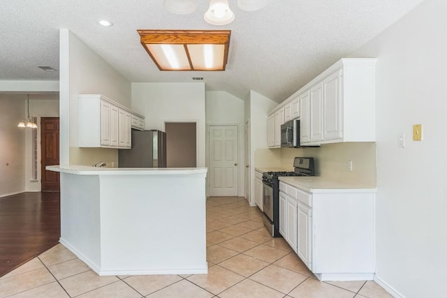 800 Mountain Ridge Dr, Leander, TX 78641 - kitchen with stainless steel appliances, lofted ceiling, a peninsula, light countertops, and white cabinetry