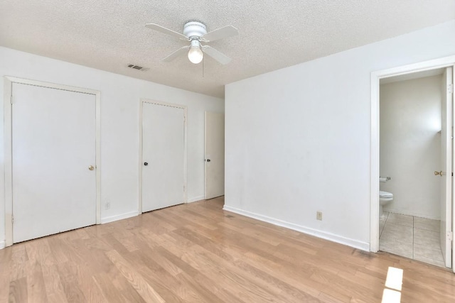 803 Easy Day Cv, Austin, TX 78745 - unfurnished bedroom featuring light wood-type flooring, a textured ceiling, connected bathroom, two closets, and ceiling fan