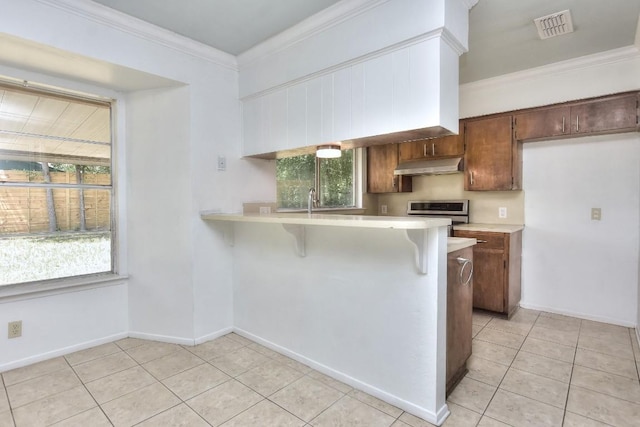 803 Easy Day Cv, Austin, TX 78745 - kitchen featuring under cabinet range hood, light countertops, light tile patterned floors, range, and a kitchen bar