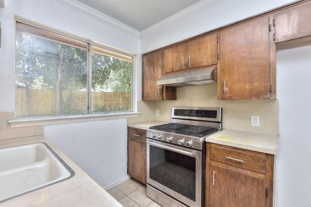 803 Easy Day Cv, Austin, TX 78745 - kitchen with stainless steel range with gas cooktop, under cabinet range hood, light tile patterned floors, crown molding, and light countertops