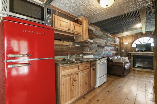 1708 Shag Bark Trl, Austin, TX 78758 - kitchen with gas range gas stove, stainless steel microwave, light wood-style floors, dark countertops, and wood walls