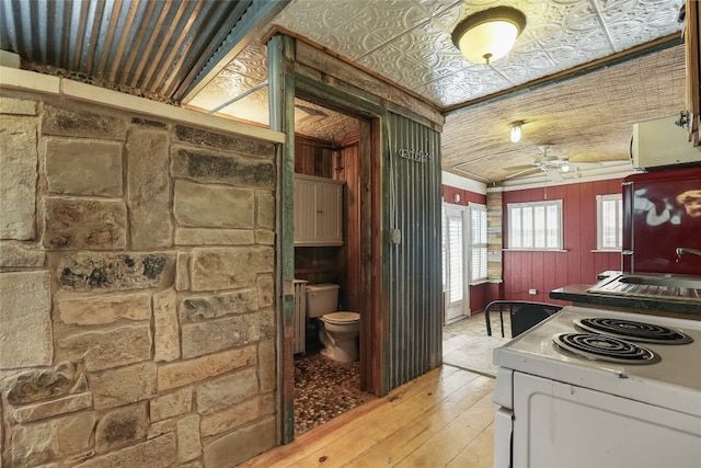 1708 Shag Bark Trl, Austin, TX 78758 - kitchen with white electric stove, light wood-style floors, ceiling fan, and wooden walls