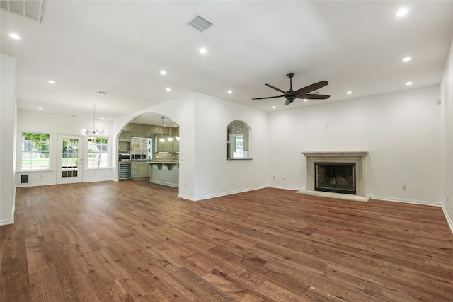 1708 Shag Bark Trl, Austin, TX 78758 - unfurnished living room featuring dark wood finished floors, a ceiling fan, a fireplace with raised hearth, recessed lighting, and arched walkways
