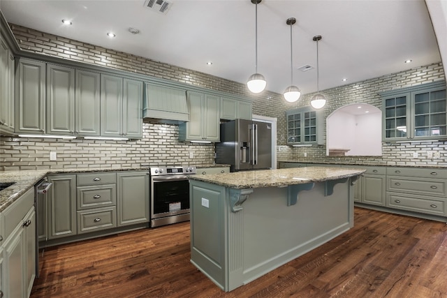 1708 Shag Bark Trl, Austin, TX 78758 - kitchen featuring appliances with stainless steel finishes, glass insert cabinets, a breakfast bar, a kitchen island, and light stone countertops