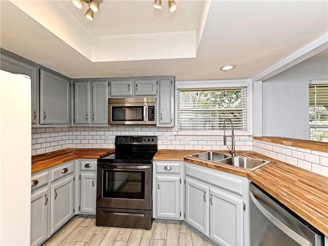 1708 Shag Bark Trl, Austin, TX 78758 - kitchen featuring stainless steel appliances, wood counters, a raised ceiling, backsplash, and recessed lighting