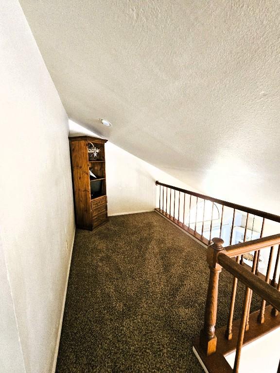 1202 Bowen Ave, Copperas Cove, TX 76522 - hall with vaulted ceiling, a textured ceiling, and dark carpet