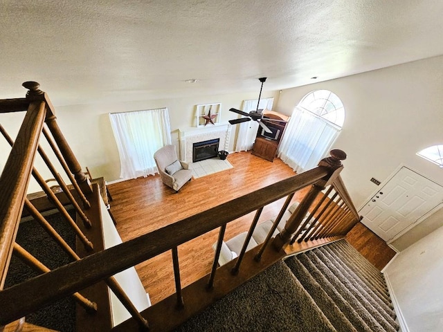 1202 Bowen Ave, Copperas Cove, TX 76522 - stairway featuring wood finished floors, a tile fireplace, a ceiling fan, and a textured ceiling