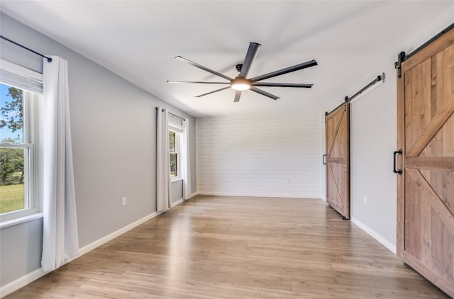 3112 Oak Ridge Dr, Horseshoe Bay, TX 78657 - spare room with a barn door, ceiling fan, light wood-style floors, and wooden walls