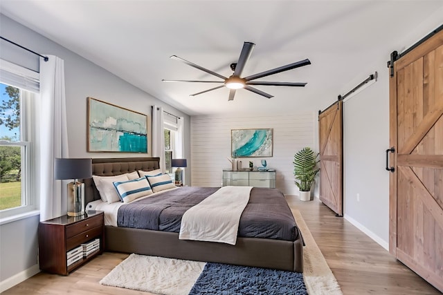 3112 Oak Ridge Dr, Horseshoe Bay, TX 78657 - bedroom featuring a barn door, light wood-style flooring, and a ceiling fan