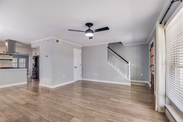 3112 Oak Ridge Dr, Horseshoe Bay, TX 78657 - unfurnished living room featuring a ceiling fan, light wood finished floors, crown molding, and stairway