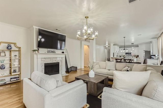 1016 Thackeray Ln, Pflugerville, TX 78660 - living room featuring a chandelier, a fireplace, and light wood-type flooring