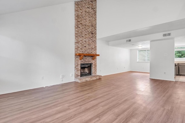 9611 Meadowheath Dr, Austin, TX 78729 - unfurnished living room featuring a towering ceiling, light wood-style floors, and a brick fireplace