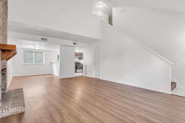 9611 Meadowheath Dr, Austin, TX 78729 - unfurnished living room with a brick fireplace, stairway, wood finished floors, and a towering ceiling