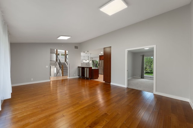 5210 Rain Creek Pkwy, Austin, TX 78759 - unfurnished living room featuring lofted ceiling, wood finished floors, stairs, and a chandelier