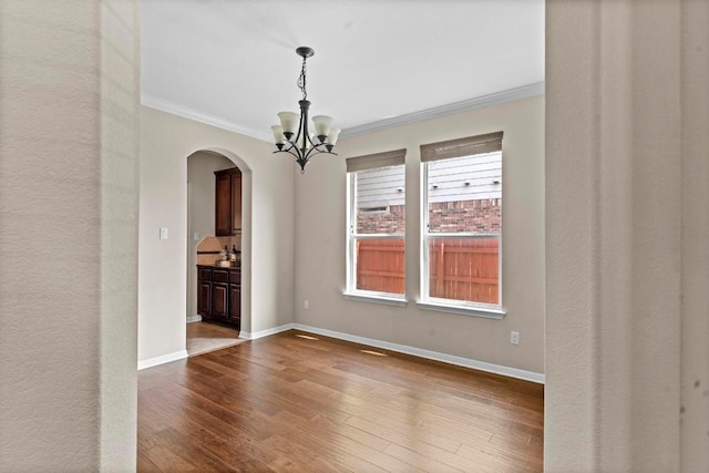 112 Florenz Ln, Georgetown, TX 78628 - unfurnished room featuring arched walkways, ornamental molding, a chandelier, and dark wood finished floors