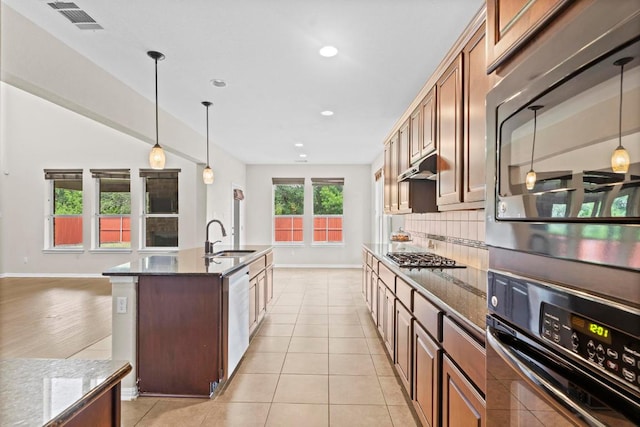 112 Florenz Ln, Georgetown, TX 78628 - kitchen with stainless steel appliances, dark stone counters, recessed lighting, under cabinet range hood, and an island with sink
