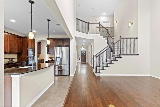 112 Florenz Ln, Georgetown, TX 78628 - kitchen with appliances with stainless steel finishes, arched walkways, light wood-style flooring, dark stone counters, and pendant lighting