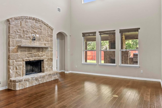 112 Florenz Ln, Georgetown, TX 78628 - unfurnished living room with hardwood / wood-style flooring, healthy amount of natural light, a fireplace, and arched walkways