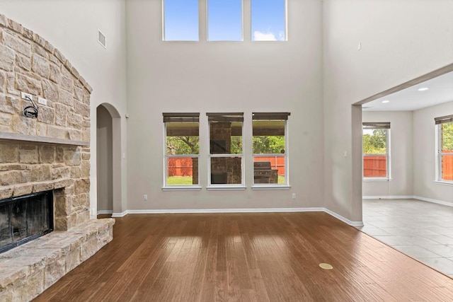 112 Florenz Ln, Georgetown, TX 78628 - unfurnished living room featuring a towering ceiling, a fireplace, hardwood / wood-style floors, and arched walkways