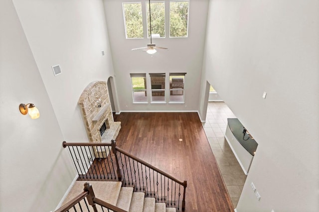 112 Florenz Ln, Georgetown, TX 78628 - stairs featuring a towering ceiling, a ceiling fan, a fireplace, and wood-type flooring