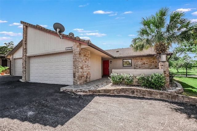 100 Bay Point Dr Unit 13, Horseshoe Bay, TX 78657 - view of front of house with stone siding, an attached garage, a tiled roof, and asphalt driveway