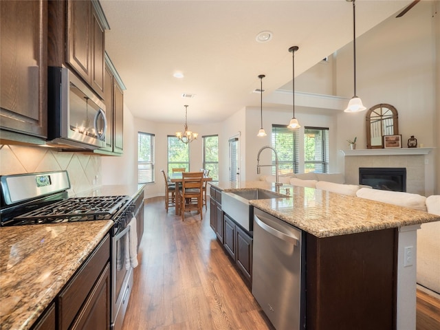 22617 Fountaingrass Ln, Lago Vista, TX 78645 - kitchen featuring appliances with stainless steel finishes, wood finished floors, a tile fireplace, dark brown cabinetry, and recessed lighting