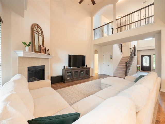 22617 Fountaingrass Ln, Lago Vista, TX 78645 - living area featuring a high ceiling, a ceiling fan, wood finished floors, stairs, and a tile fireplace