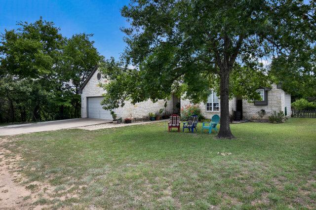 1906 W Moeta Dr, Austin, TX 78734 - view of property hidden behind natural elements with stone siding, driveway, a front yard, and a garage