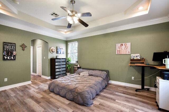 1906 W Moeta Dr, Austin, TX 78734 - bedroom featuring a raised ceiling, arched walkways, wood finished floors, ornamental molding, and a desk