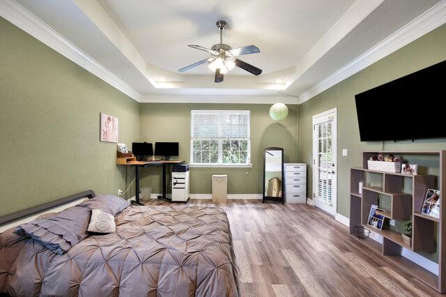 1906 W Moeta Dr, Austin, TX 78734 - bedroom with a tray ceiling, wood finished floors, a desk, crown molding, and a ceiling fan